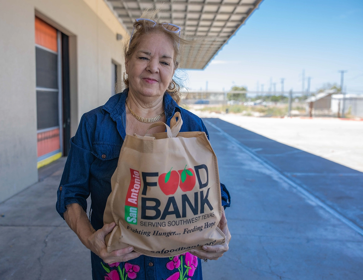Woman holding San Antonio Food Bank produce bag.