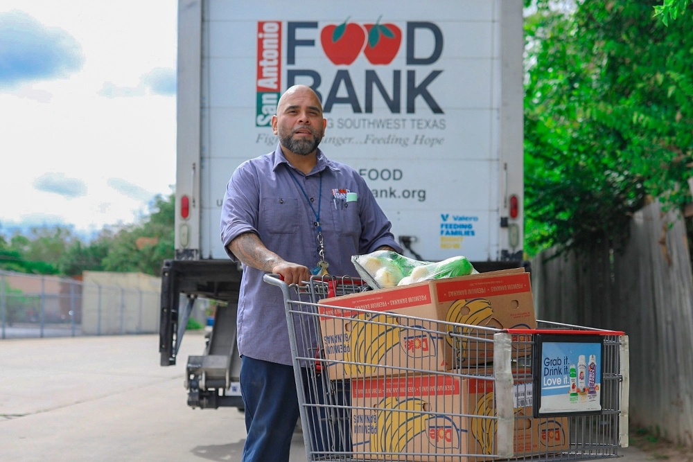Food Bank employee pushing grocery cart full of produce.